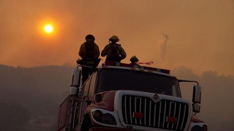 Firefighters watch a helicopter extinguish fires in THE WEST IS BURNING (Photo courtesy of Landmark Stories via KCET).