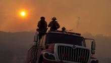 Firefighters watch a helicopter extinguish fires in THE WEST IS BURNING (Photo courtesy of Landmark Stories via KCET).